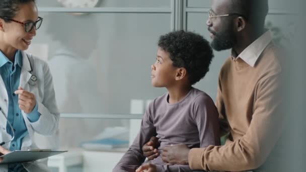 Наклоните Снимок Маленького Афроамериканского Мальчика Сидящего Отцом Медицинском Диване Клинике — стоковое видео