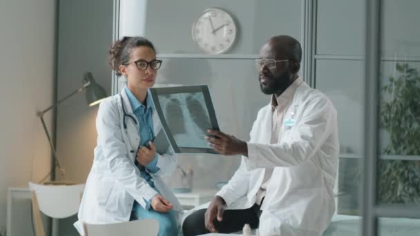 Klinikte Çalışırken Afrikalı Amerikalı Bir Erkek Meslektaşla Göğüs Röntgenini Tartışan — Stok video