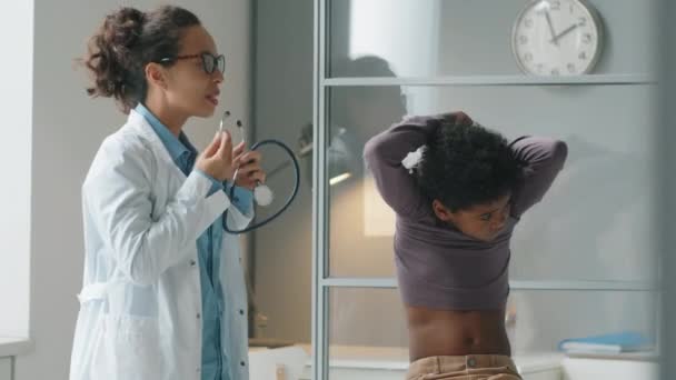 Smíšené Rasy Ženské Pediatr Bílém Plášti Poslouchá Záda Malého Afroameričana — Stock video