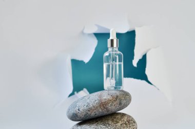 Doğal taşın üzerindeki beyaz şişelerde kozmetik tonik serumu. Mavi arkaplan, doğal cilt ürünleri konsepti.