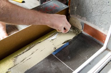 İşçi elleri spatula kullanıyor ve tavanı macunla sıvamış, yani ağır iş. Bölünmüş ağ, yakın çekim