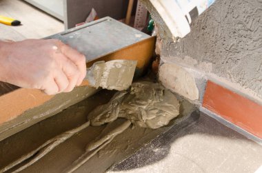 İşçi elleri spatula kullanıyor ve tavanı macunla sıvamış, yani ağır iş. Bölünmüş ağ, yakın çekim