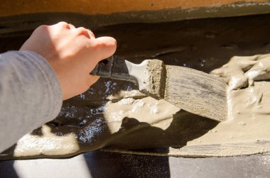 İşçi elleri spatula kullanıyor ve tavanı macunla sıvamış, yani ağır iş. Bölünmüş ağ, yakın çekim