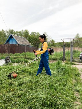 Güzel kız çimleri kesiyor. Çim biçiyorum. Yeşil çimlerin üzerindeki hava manzaralı güzel kadın çim biçme makinesi. Çim biçme ekipmanı. Çim biçme makinesi. Havadan çim biçme