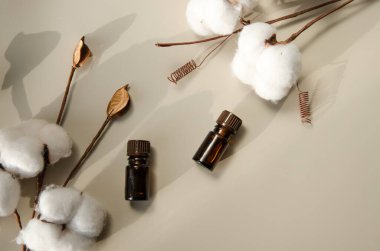 Bej arka planda çevre dostu biyokozmetik seti. Güzellik ürünleri - Kehribar cam damlatan şişeler ve pamuk yaprakları. Düz yatış, üst görünüm.