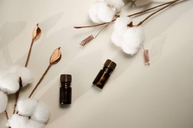 Bej arka planda çevre dostu biyokozmetik seti. Güzellik ürünleri - Kehribar cam damlatan şişeler ve pamuk yaprakları. Düz yatış, üst görünüm.