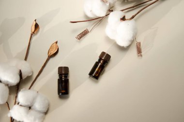 Bej arka planda çevre dostu biyokozmetik seti. Güzellik ürünleri - Kehribar cam damlatan şişeler ve pamuk yaprakları. Düz yatış, üst görünüm.