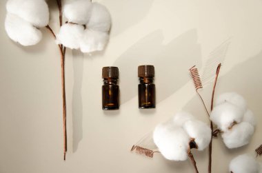 Bej arka planda çevre dostu biyokozmetik seti. Güzellik ürünleri - Kehribar cam damlatan şişeler ve pamuk yaprakları. Düz yatış, üst görünüm.