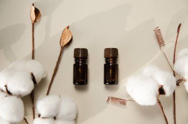 Bej arka planda çevre dostu biyokozmetik seti. Güzellik ürünleri - Kehribar cam damlatan şişeler ve pamuk yaprakları. Düz yatış, üst görünüm.