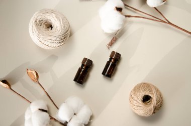 Bej arka planda çevre dostu biyokozmetik seti. Güzellik ürünleri - Kehribar cam damlatan şişeler ve pamuk yaprakları. Düz yatış, üst görünüm.