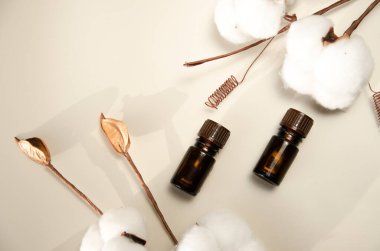 Bej arka planda çevre dostu biyokozmetik seti. Güzellik ürünleri - Kehribar cam damlatan şişeler ve pamuk yaprakları. Düz yatış, üst görünüm.