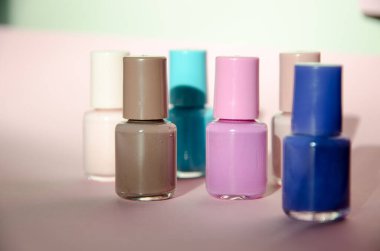 Pembe arka planda izole edilmiş bir grup pastel renkli tırnak cilası.