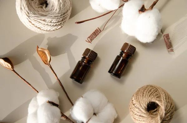 Bej arka planda çevre dostu biyokozmetik seti. Güzellik ürünleri - Kehribar cam damlatan şişeler ve pamuk yaprakları. Düz yatış, üst görünüm.