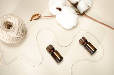 Bej arka planda çevre dostu biyokozmetik seti. Güzellik ürünleri - Kehribar cam damlatan şişeler ve pamuk yaprakları. Düz yatış, üst görünüm.