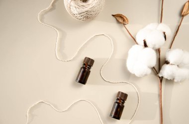 Bej arka planda çevre dostu biyokozmetik seti. Güzellik ürünleri - Kehribar cam damlatan şişeler ve pamuk yaprakları. Düz yatış, üst görünüm.