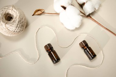 Bej arka planda çevre dostu biyokozmetik seti. Güzellik ürünleri - Kehribar cam damlatan şişeler ve pamuk yaprakları. Düz yatış, üst görünüm.