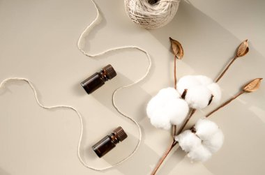 Bej arka planda çevre dostu biyokozmetik seti. Güzellik ürünleri - Kehribar cam damlatan şişeler ve pamuk yaprakları. Düz yatış, üst görünüm.