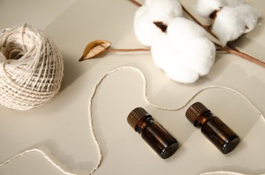 Bej arka planda çevre dostu biyokozmetik seti. Güzellik ürünleri - Kehribar cam damlatan şişeler ve pamuk yaprakları. Düz yatış, üst görünüm.