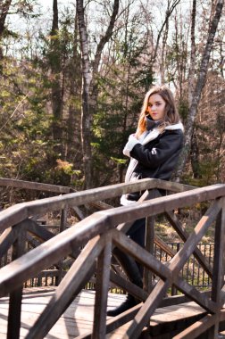 Köprüdeki güzel esmer kızın portresi. Şehirde atkı ve sonbahar ceketi var. Sokakta yürüyen iş kadınının inanılmaz manzarası..