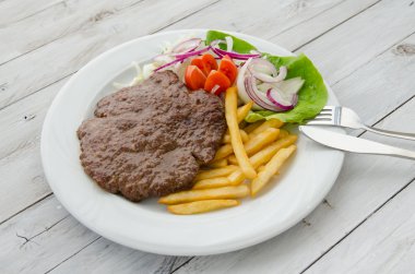 Hamburger ve kızarmış patates ve bir tabak salata ile servis