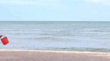 Gündüz vakti çocuklarla sahilde dalgalar esiyor. Dalgalar boş kumsala vuruyor.