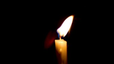 Alevlerin, siyah arka planda izole edilmiş bir şekilde mumun üzerinde yandığı yakın plan. Karanlıkta mum alevi.