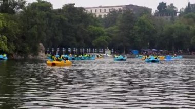 Mexico City, Mexico- June 2021: Families having fun on a boat on Lake Chapultepec, with the castle of Chapultepec in the background.
