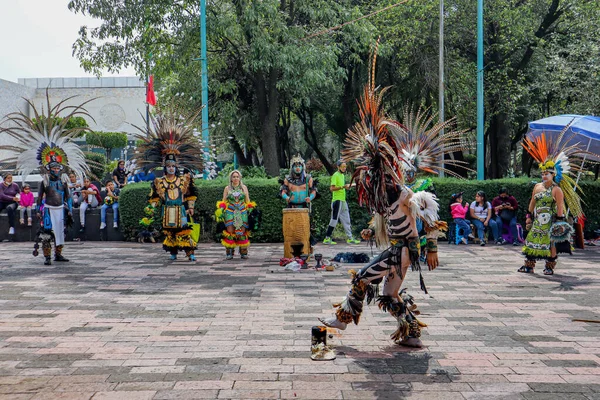Mexico City, Meksika - Haziran 2021: Aztek döneminden kalma giyinmiş bir adam davulun ritmiyle dans ederken, arkadaşları ve turistler onu izliyorlar..