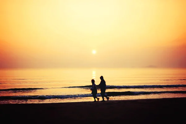 Silhouette of couple running on the beach — Stock Photo, Image