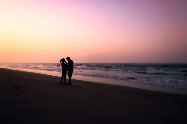 Silhouet van paren knuffelen op het strand — Stockfoto