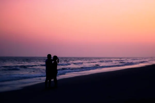 Silhouet van paren knuffelen op het strand — Stockfoto