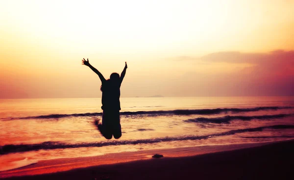 Silhouette einer Frau, die am Strand springt — Stockfoto