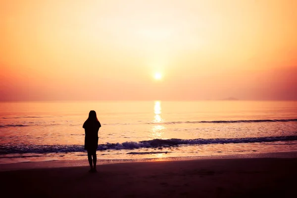 Siluett av kvinna ensam och våg på stranden Royaltyfria Stockfoton
