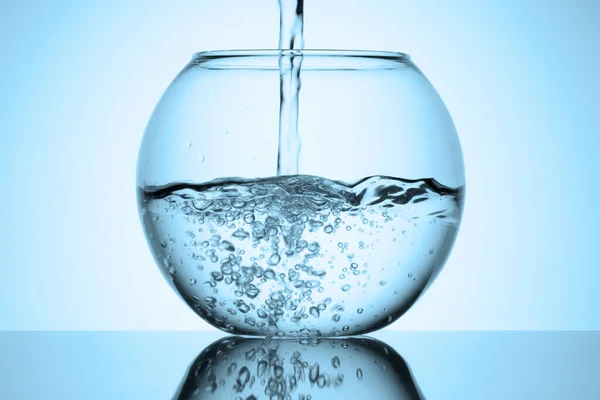 白い背景の反射ガラスの表面に透明な水槽の中に水が流れ込みます 冷たい青 — ストック写真