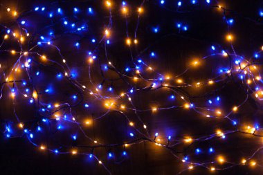 Noel, ışıldayan çelenklerle dolu şenlikli bir arka plan. Karanlık bir arka planda renkli ışıklar. Yeni yıl kartları, kartpostallar, afişler. Metin için yeri var. Yumuşak odak.