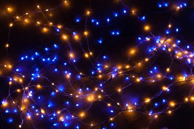 Noel, ışıldayan çelenklerle dolu şenlikli bir arka plan. Karanlık bir arka planda renkli ışıklar. Yeni yıl kartları, kartpostallar, afişler. Metin için yeri var. Yumuşak odak.