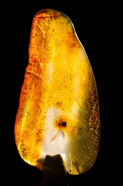 Siyah zemin üzerinde izole edilmiş ham kehribar taşının makro yakın çekimi.