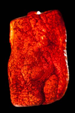 Siyah zemin üzerinde izole edilmiş ham kehribar taşının makro yakın çekimi.