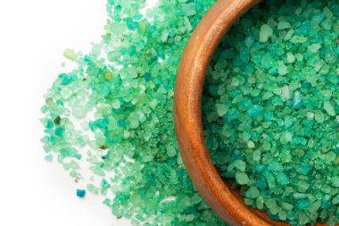 Beyaz arka planda izole edilmiş ahşap bir kaseye yeşil kozalaklı ağaç eklenmiş banyo tuzu. Düz üst görünüm.