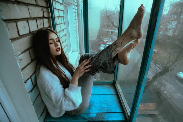 漂亮的年轻性感姑娘在阳台上摆姿势 现代风格的女孩的艺术摄影肖像 照片上有坐姿和附加的噪音 — 图库照片