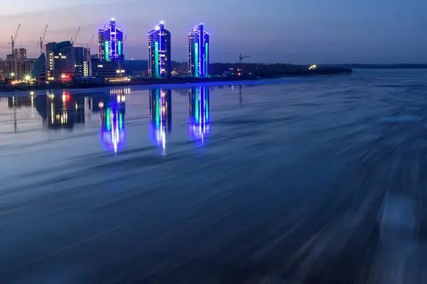 风景秀丽的夜景与打破冰在河上与快速流动在城市的背景上与灯光和反射在水中 在长时间曝光 — 图库照片