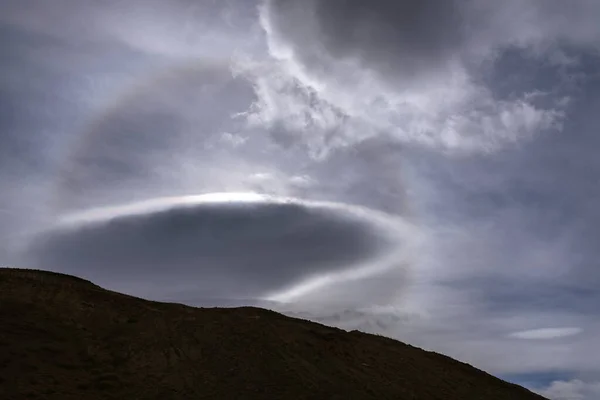 Amazing view of beautiful cloud patterns and circular sun halo in the sky above the mountains