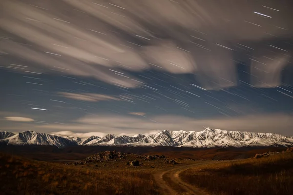 秋の月明かりの下で雪の山の上の空のトラックの形で雲や星とカラフルな夜の風景 — ストック写真