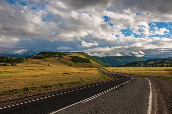 Road in the steppe and mountains at sunset — Stock Photo, Image