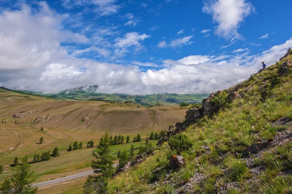 A young man is sitting on a mountain slope — Stock Photo, Image