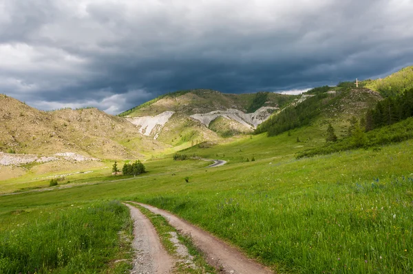 Horské údolí louka silniční mraky — Stock fotografie