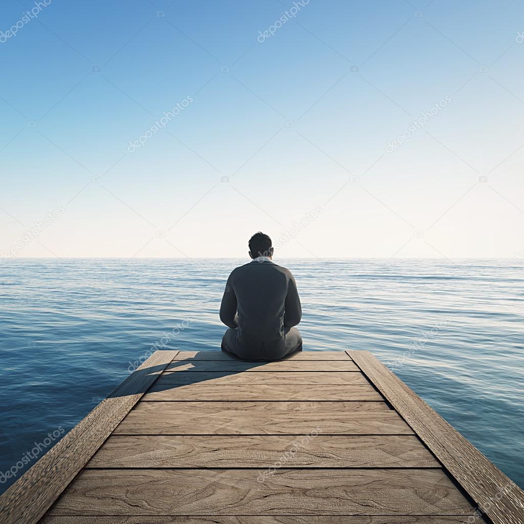 Man sits at wharf and looking at the sea.