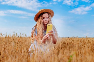 Woman in golden wheat field, backpack travel to European countryside, active lifestyle, taking pictures, active summer vacation concept