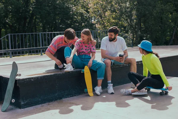 화창 한 날, 친구들은 매우 매력적 이고 다양 한 민족이 모여 현대적 인 스케이트 공원에서 시간을 즐기면서 바닥에 앉아서 스케이트를 타기 전에 사교 활동을 한다 — 스톡 사진