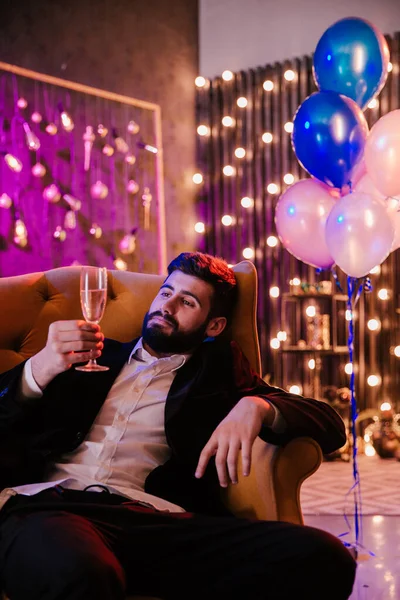 Chico joven de buen aspecto en un traje casual disfrutando de la noche en la fiesta bebiendo un poco de vino espumoso ambiente de fiesta grande —  Fotos de Stock